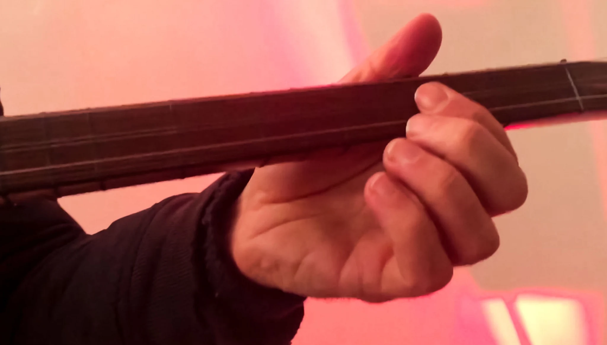 Close view of a musician's hand on the long neck of the saz